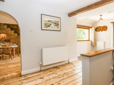 A hallway with wooden floors a radiator and a painting above it at Bunts Barn Northlew near Hatherleigh