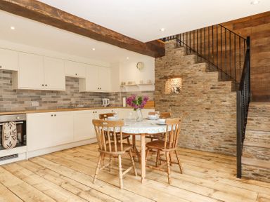 A kitchen with a wooden dining table and chairs beside a stone staircase at Bunts Barn Northlew near Hatherleigh