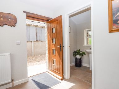 An entrance with a wooden door open to the outside and a small room with a sink and plant at Bunts Barn Northlew near Hatherleigh