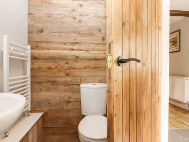 A bathroom with a toilet sink towel rail and wooden panelled walls at Bunts Barn Northlew near Hatherleigh