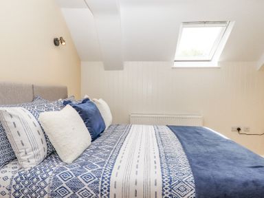 A bedroom with a bed with blue and white patterned bedding and pillows under a skylight window at Bunts Barn in Northlew near Hatherleigh