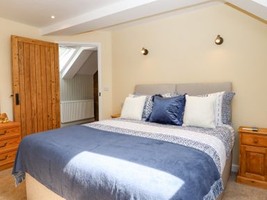 A bedroom with a bed with blue and white bedding and wooden bedside tables at Bunts Barn in Northlew near Hatherleigh