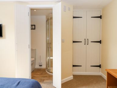 A bedroom with an open door showing a bathroom with a shower and toilet and a closed white closet at Bunts Barn in Northlew near Hatherleigh