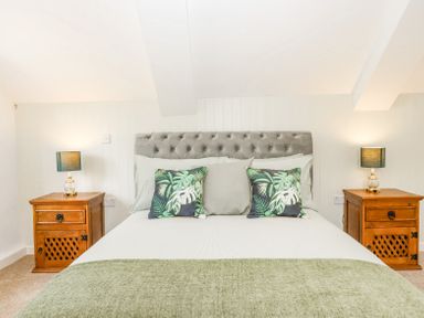 A bedroom with a bed with green and white bedding and two wooden bedside tables with lamps at Bunts Barn Northlew near Hatherleigh