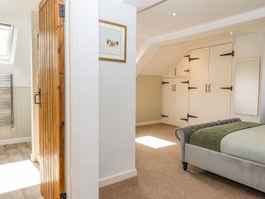 A bedroom with bed and built in cupboards next to a partially open wooden door at Bunts Barn Northlew near Hatherleigh