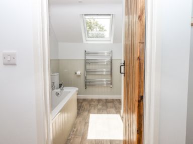 A bathroom with a bathtub toilet towel rack wooden floor and a skylight window at Bunts Barn in Northlew near Hatherleigh