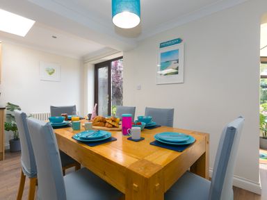 A dining room with a wooden table set with blue plates and cups and croissants on the table at Spernenwyn in St Ives