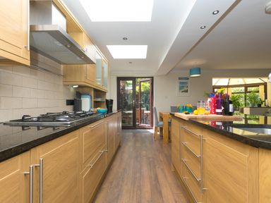 A kitchen with wooden cabinets a black countertop a gas stove and a dining area at Spernenwyn St Ives