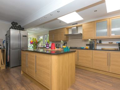 A kitchen with wooden cabinets an island cooker hood and a refrigerator at Spernenwyn in St Ives