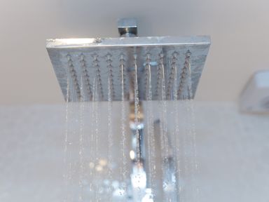 A shower head with water flowing from it in a bathroom at Spernenwyn in St Ives