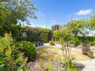 A garden with grass lawn trees shrubs potted plants and a wooden gate at Spernenwyn in St Ives