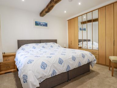 A bedroom with a bed bedside tables and a wardrobe with mirrored doors at Harvenna Cottage in Crackington Haven