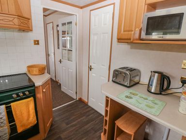 A kitchen with an oven towels bowl toaster kettle microwave and a stool at Park Lane in Llanteg near Kilgetty