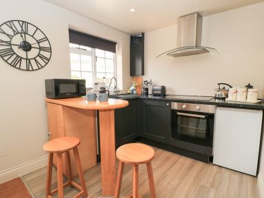 A kitchen with a bar and stools at Well Cottage Nr Malmesbury