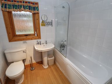 A bathroom with a toilet sink bathtub window and wooden floor at The Great Escape in Kenwick near Louth