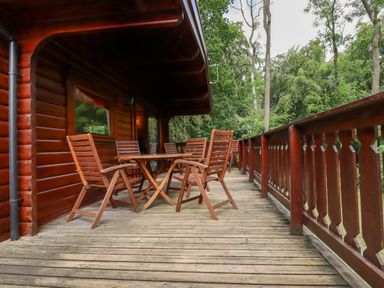 A wooden balcony with table and chairs overlooking trees at The Great Escape in Kenwick near Louth