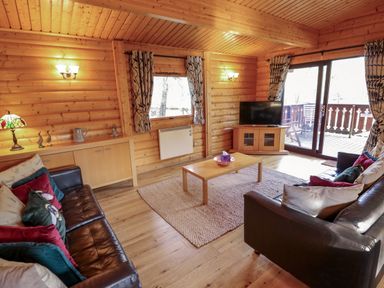 A living room with two leather sofas a coffee table a television and sliding glass doors at The Great Escape in Kenwick near Louth