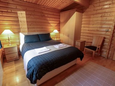 A bedroom with a double bed two bedside tables with lamps a wardrobe a chair and a rug at The Great Escape in Kenwick near Louth