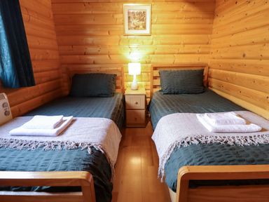 A bedroom with two single beds with dark bedspreads and folded towels on each bed at The Great Escape in Kenwick near Louth