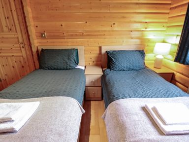 A bedroom with two single beds a bedside table and a lamp in a wooden room at The Great Escape in Kenwick near Louth