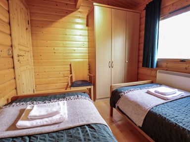 A bedroom with two single beds with towels on them a wooden chair a wardrobe and a window at The Great Escape in Kenwick near Louth