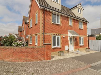 A brick house with multiple windows and a white door with small planters outside at 12 Clos Yr Wylan in Barry