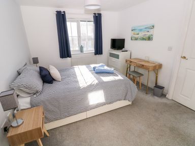 A bedroom with a bed a bedside table a dresser a desk and a window with curtains at 12 Clos Yr Wylan Barry