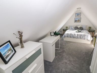 A bedroom with a bed a desk a chest of drawers and framed pictures at 12 Clos Yr Wylan in Barry