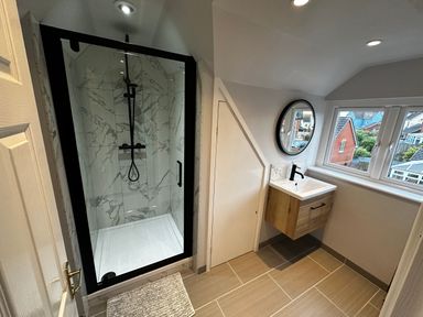 A bathroom with a glass shower enclosure a wall-mounted sink and a round mirror above the sink at 12 Clos Yr Wylan Barry