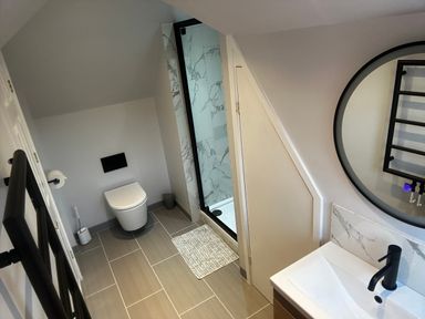 A bathroom with a toilet shower sink and round mirror at 12 Clos Yr Wylan in Barry