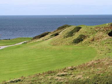 A coastal grassy landscape with a path and ocean view at Glan Awel in Nefyn