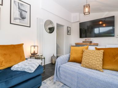 A living room with two sofas and a large wall mounted television at Pennant Cottage in Llithfaen