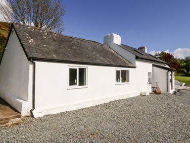 A white single-story cottage with a slate roof and gravel driveway at Pennant Cottage in Llithfaen