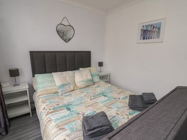 A bedroom with a double bed and pillows two bedside tables with lamps and towels on the bed at Ty Cwtch in Llangynin near St Clears
