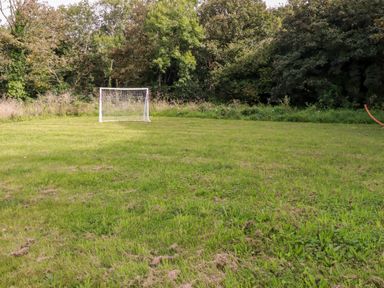 A grassy field with a white soccer goal and trees in the background at Carines Barns Pol Cubert