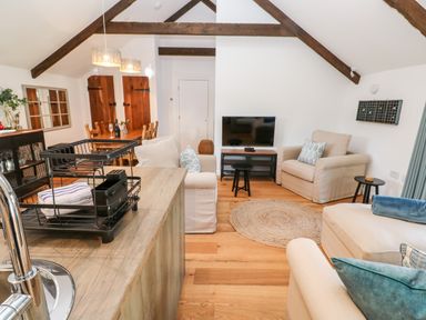 An open living and dining area with wooden beams a TV and beige sofas at Carines Barns - Pol in Cubert