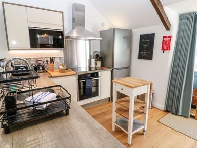 A kitchen with a microwave oven stove refrigerator and a small wooden kitchen cart at Carines Barns - Pol in Cubert
