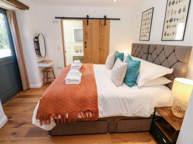 A bedroom with a bed with pillows and folded towels and a bedside table lamp at Carines Barns - Pol in Cubert