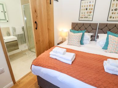 A bedroom with a double bed and an adjoining bathroom at Carines Barns - Pol in Cubert