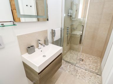A bathroom with a sink vanity and a walk-in shower with pebble flooring at Carines Barns - Pol in Cubert