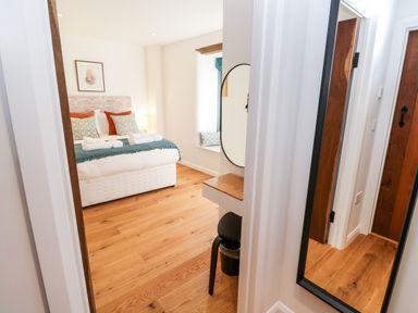 A bedroom with a bed with folded towels and pillows a small vanity with a mirror and a chair visible at Carines Barns - Pol in Cubert