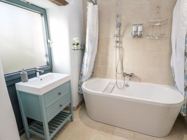 A bathroom with a bathtub a shower and a sink with a cabinet at Carines Barns - Pol in Cubert