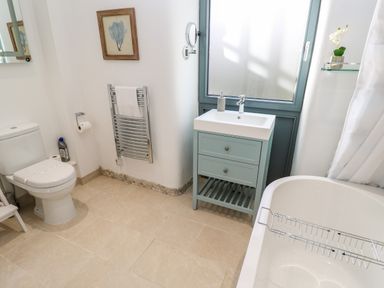 A bathroom with a toilet a sink with a cabinet a bathtub and a towel radiator at Carines Barns - Pol in Cubert