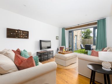 A living room with a television and soft seating area at Carines Barns - Pen, Cubert