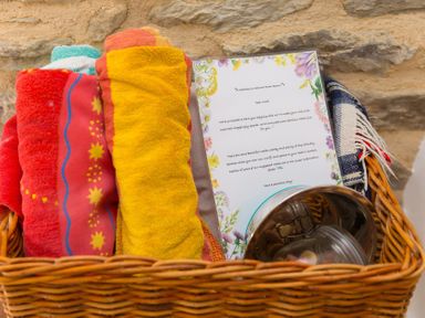A basket with towels and a welcome note at Carines Barns - Pen, Cubert