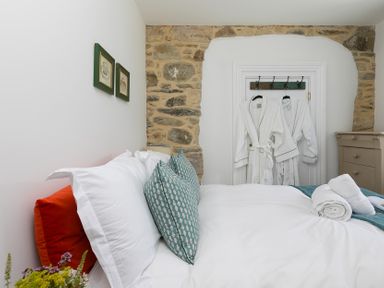 A bedroom with a bed and robes hanging in the closet at Carines Barns - Pen, Cubert