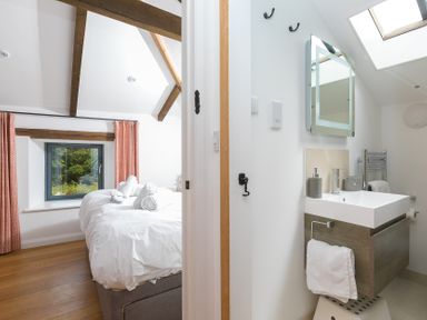 A bedroom with a bed and window leading to an adjoining bathroom at Carines Barns - Pen, Cubert