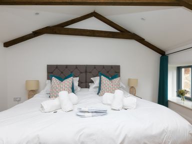 A bedroom with a large bed and pillows at Carines Barns - Pen in Cubert