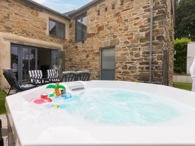 A hot tub with accessories and seating at Carines Barns - Pen, Cubert