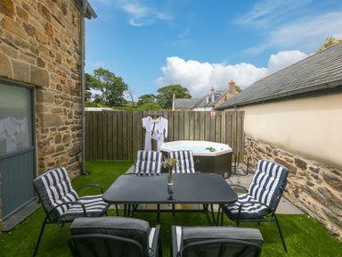 An outdoor area with seating and a hot tub at Carines Barns - Pen Cubert